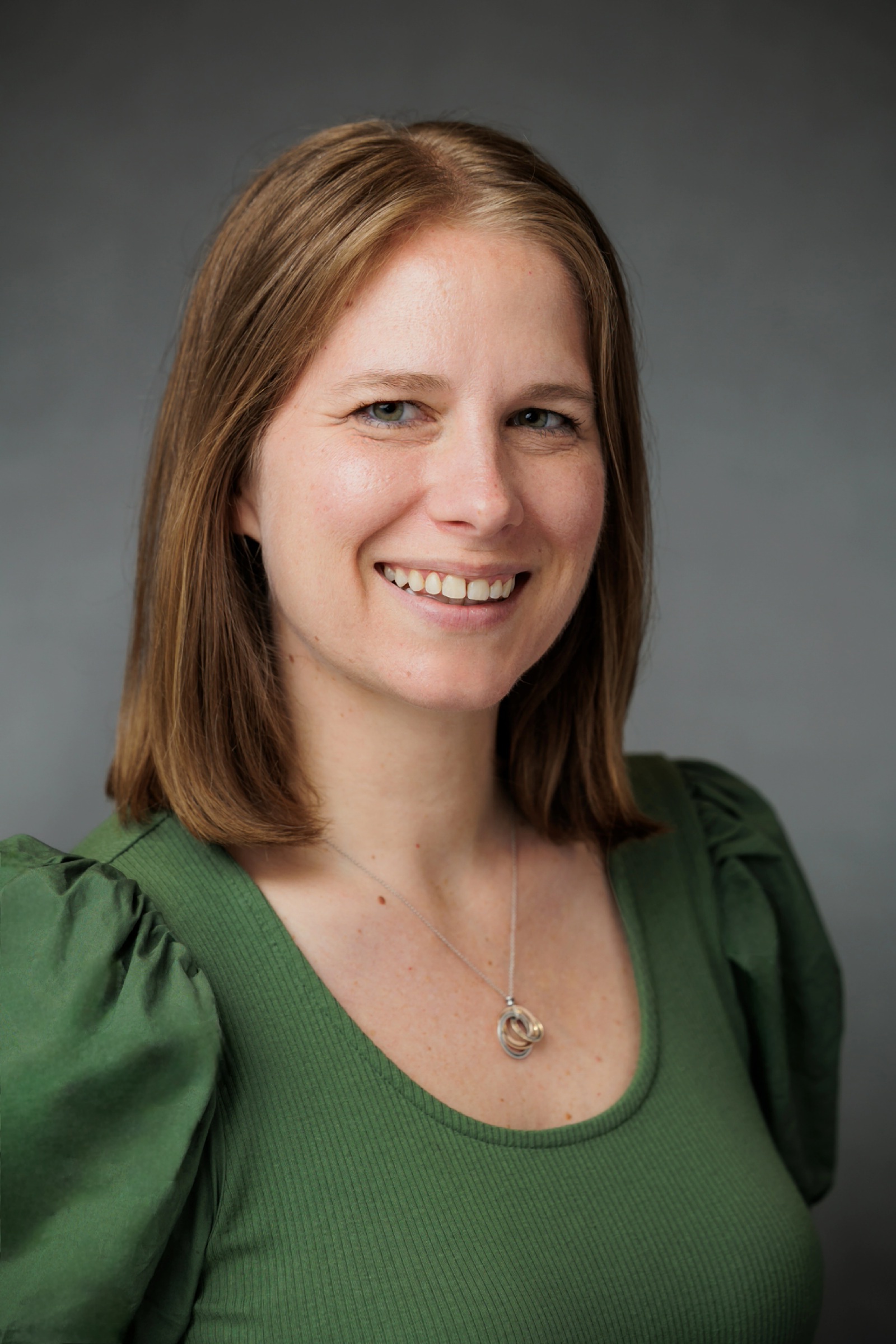 Robyn's headshot (in a green dress, facing right)